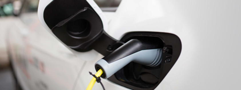 Ladekabel steckt an einem E-Auto und lädt es auf.