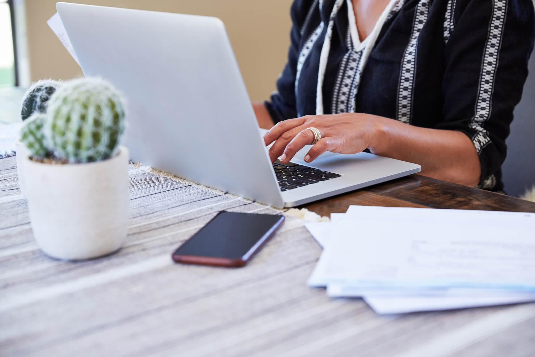 Frau tippt etwas auf ihrem Laptop und ihr Handy liegt daneben