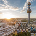 Die Wiener Stadtlandschaft bei Sonnenuntergang mit einem einzigartigen hohen Turm der Spitttelau und modernen Gebäuden im Vordergrund.